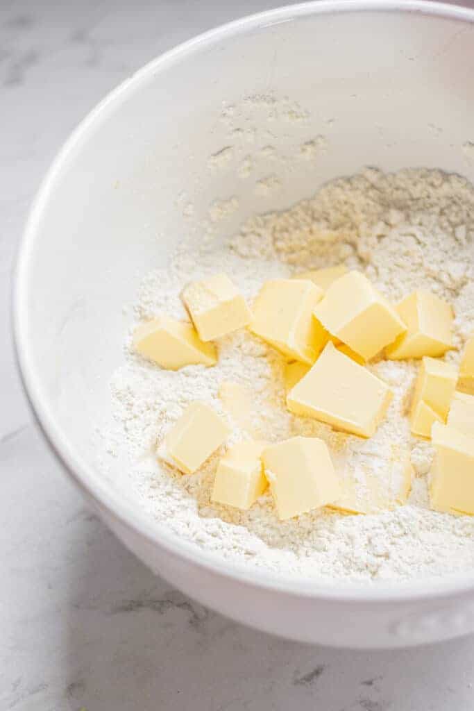 a bowl of flour with chunks of butter.