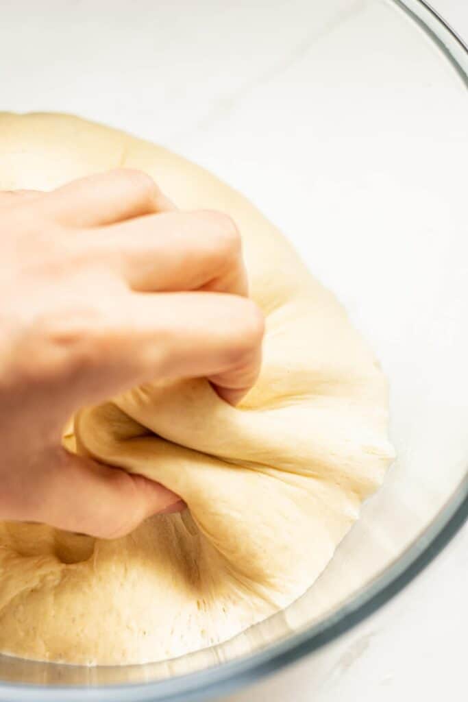 a hand pulling dough out of a bowl.