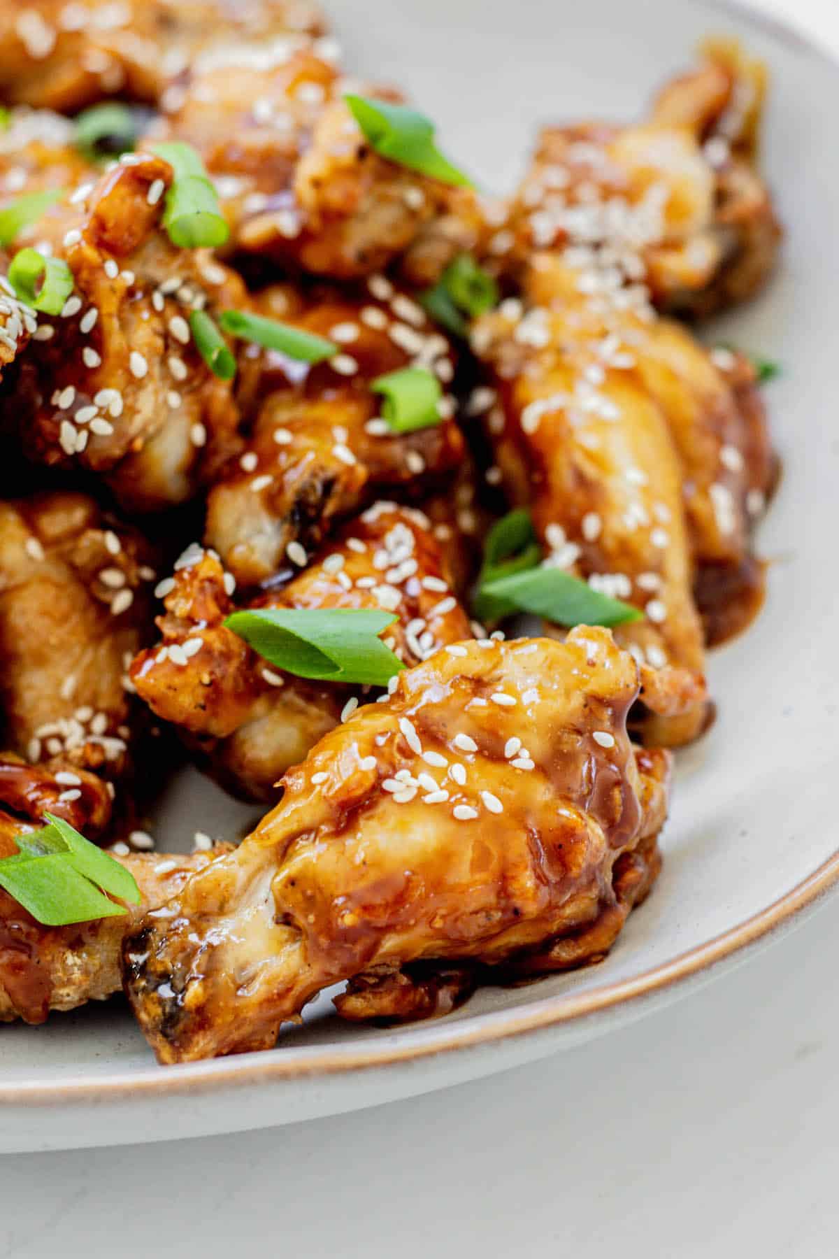 a plate of chicken wings with teriyaki and sesame seeds.